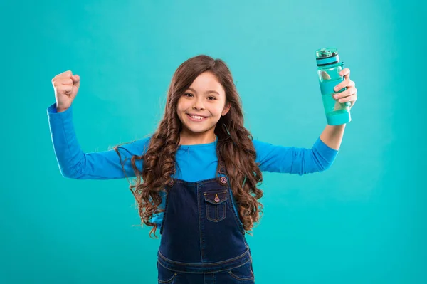 Gesund und hydratisiert. Mädchen kümmert sich um Gesundheit und Wasserhaushalt. Mädchen fröhlich halten Wasserflasche blauen Hintergrund. Mädchen mit langen Haaren hat eine Wasserflasche. Wasserhaushaltskonzept. starkes und gesundes Kind — Stockfoto