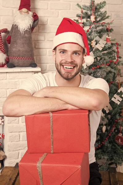 Man in kerstman hoed glimlach met dozen bij kerstboom — Stockfoto