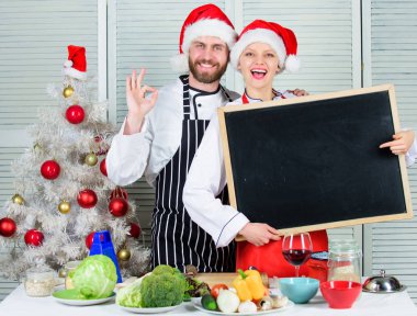 Noel yemeği için çift onay listesi malzemeler. Bizim aile için yemek listesi. Christmas yemek yemek. Erkek ve kadın şef santa şapka Noel ağacı yakınındaki blackboard kopya alanı tutun. Noel tarifi kavramı