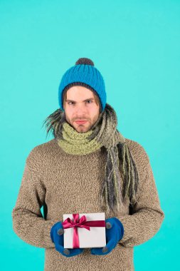 Senin için bir şey var. Adam yakışıklı giyim kış şapka atkı eldiven hediye kutusu tutun sakallı. Hipster Noel hediyesi yay ile tutun. Tatil hediyesi kavramı. Kış tatili. Hediye yayılan mutluluk vermek