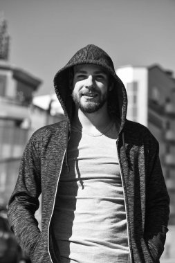 Sakal konsepti. Tıraşsız suratlı sakallı bir adam. Kapüşonlu genç adam güneşli açık havada