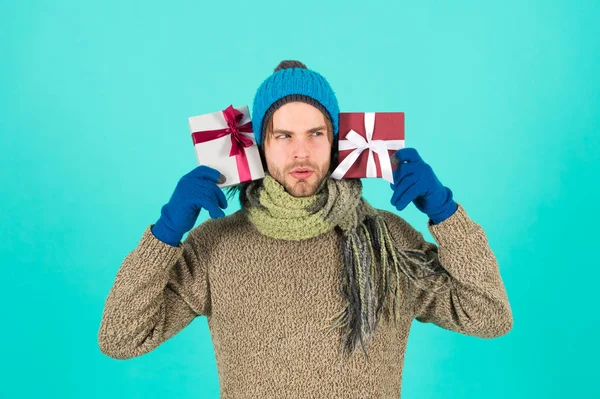 What is inside. Man bearded handsome wear winter hat scarf gloves hold two gift boxes. Hipster hold christmas gift with bow. Holiday present concept. Winter holidays. Give gift spread happiness