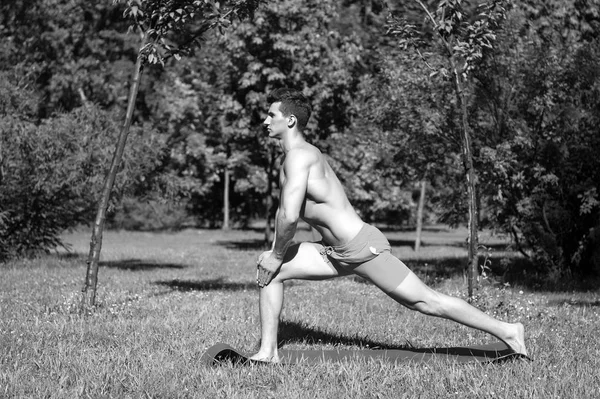 Aptitud. musculoso hombre de entrenamiento en la alfombra de fitness al aire libre. actividad de verano fitness. Hombre de fitness en hierba verde. estiramiento . — Foto de Stock