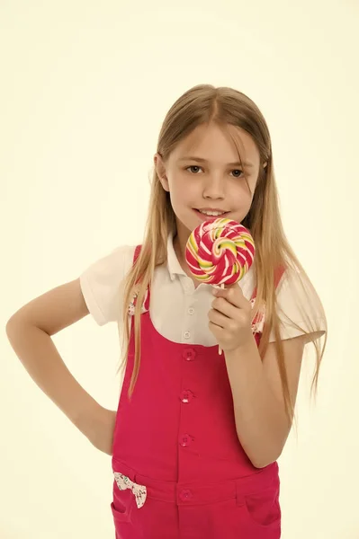 Süße Optik. kleines Mädchen essen Bonbons auf Stick isoliert auf weiß. Kinderlächeln mit Lutscher. glückliches Kind mit wirbelndem Karamell. Essen und Dessert. Ernährung und Diät — Stockfoto