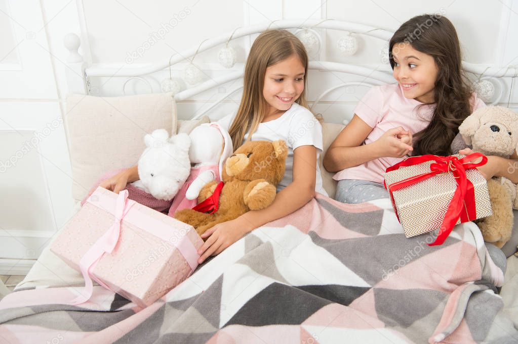 Merry christmas and cheerful children. Christmas morning concept. Girls kids wake up on christmas morning. Lets open christmas gifts. Sisters best friends with toys relax in bed with gift boxes