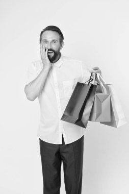 Olgun sakallı, neşeli yüzlü bir adam alışveriş torbaları tutuyor. Adamın beklenmedik yetenekleri var. Hediye sarısı arka plana şaşıran adam. Hediyeler hayatımızı daha ilginç kılıyor. Müşteri için ikramiye her zaman iyi fikirdir..