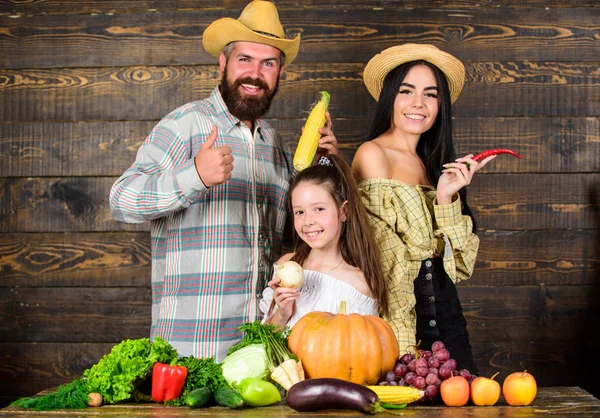 Family rustic style farmers at market with vegetables fruits and greenery. Family farm concept. Family farmers with harvest wooden background. Parents and daughter celebrate autumn harvest festival