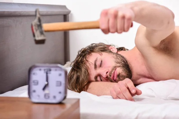 Un sonido molesto. Deja de sonar. Molesto despertador sonando. Hombre barbudo molesto cara somnolienta yacía almohada cerca del despertador. Un tipo tocando con un martillo sonando el despertador. Régimen de disciplina de ruptura — Foto de Stock