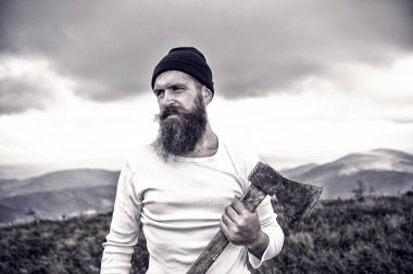 sakallı adam, bulutlu gökyüzü ile dağ üst balta tutar