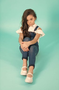 Küçük kız kot pantolon uzun saçlı katta oturmak