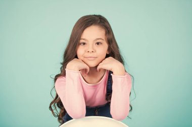 Uzun esmer saçlı, saç stiliyle gülümseyen bir çocuk modeli.