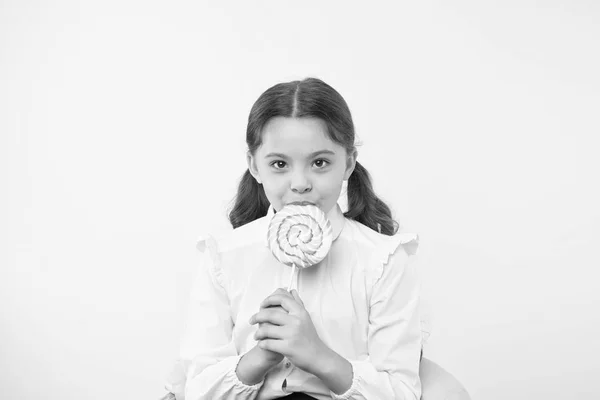 Problema comum da desnutrição. Menina aluna escola uniforme gosta de doces pirulito doce fundo amarelo. Menina bonito garoto rabo de cavalo penteado comer pirulito doce. Doces em porções apropriadas ok — Fotografia de Stock