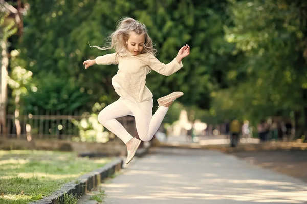 Söt liten tjej med lockigt blont hår hoppning på gatan — Stockfoto