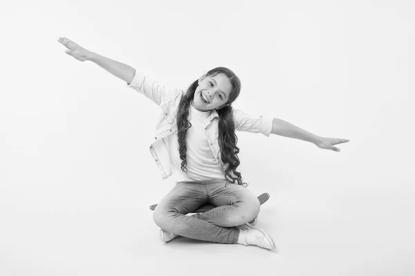 Mädchen sitzen Penny Board gelbem Hintergrund. Kinderlächelnde Gesichter täuschen vor, auf dem Skateboard zu fliegen. Kinder entspannen sitzen Penny Board. Unbekümmert fröhliche Fahrt. Hobby oder Lieblingsaktivität aus der Kindheit. Hobby der jungen Generation — Stockfoto