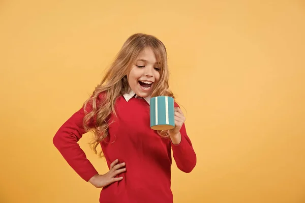 Ребенок с удивленным лицом держать синюю чашку на оранжевом фоне — стоковое фото