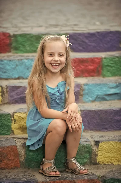 Petite fille heureuse en robe bleue sur des escaliers colorés — Photo