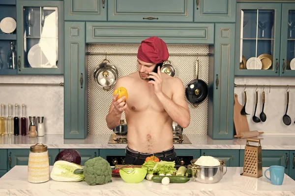 Macho cuoco con torso sexy parlare sul telefono cellulare in cucina. Chef con peperoncino giallo vegetale. Menù vegetariano e dieta sana. Preparazione del cibo e ricette di cottura. Comunicazione e nuove tecnologie — Foto Stock