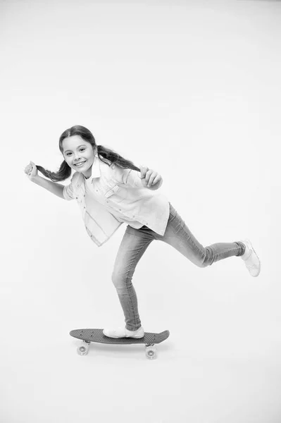 女の子に乗るペニー ボード黄色背景。子供ペニー ボードを楽しんでいます。屈託のない幸せな乗り心地。子供の頃からの趣味の好きな活動。若い世代の趣味。子供の笑顔がスケート ボードの上に立つ — ストック写真