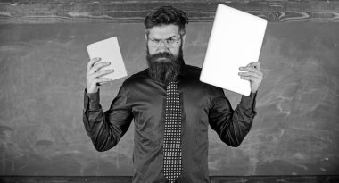 Dijital kağıt karşı. Öğretmen sakallı hippi kitap ve laptop tutar. Ne tercih ederim. Öğretmen modern öğretim yaklaşımı seçme. Şu öğretim yöntemi seçin. Kağıt kitap dizüstü karşı