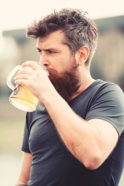 Zanaat bira kavramı. Uzun sakallı adam rahat görünüyor. Sakal ve bıyık sıkı ya da ciddi yüz, açık renkli, defocused olan adam. Sakallı adam bira bardağı tutan, içecekler bira açık