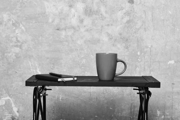 Bebidas quentes e conceito de blog. Caderno com marcador, caneta e copo vermelho na mesa perto da parede. Diário com caneta e nova xícara de bebida da manhã dentro de casa. Chá ou café na mesa preta no interior moderno — Fotografia de Stock