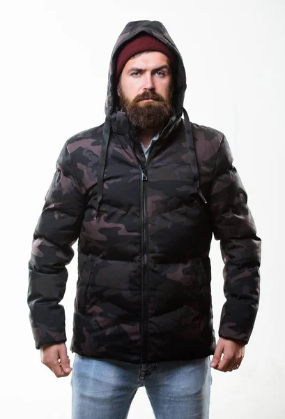 Cómodo atuendo de invierno. Invierno ropa de hombre elegante. Hombre barbudo soporte cálido camuflaje patrón chaqueta parka aislado sobre fondo blanco. Moda de invierno Hipster. Chico usar sombrero y chaqueta de invierno negro —  Fotos de Stock