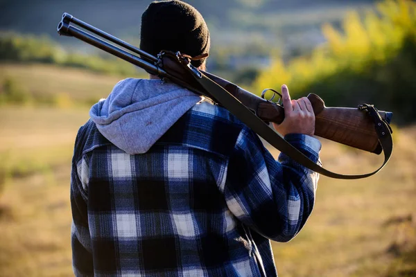 Caccia maschile hobby concetto di svago. Uomo brutale ragazzo guardiacaccia in sfondo cappello natura. Brutalità e mascolinità. Hunter portare pistola da fucile sulla spalla vista posteriore. Guy cacciatore trascorrere il tempo libero caccia — Foto Stock