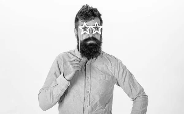 Чоловік тримає партійні окуляри у формі зірок, білий фон. Гіпстер з бородою і вусами на веселому здивованому обличчі позує зірковими окулярами, копіює простір. концепція суперзірки — стокове фото