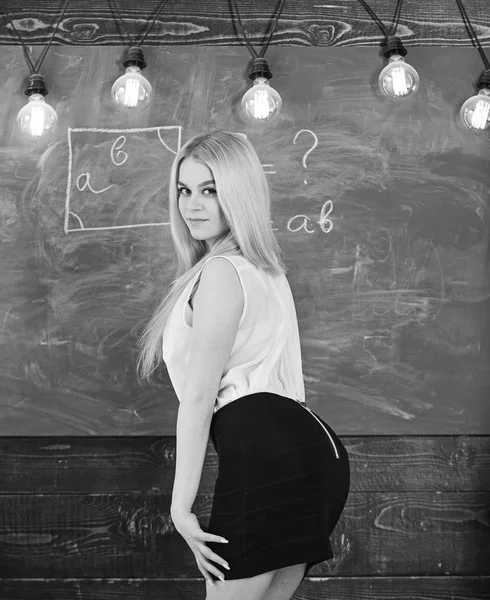 Lady sexy teacher in short skirt looking back while explaining formula. Sexy teacher concept. Woman with nice buttocks teaching mathematics. Teacher of mathematics writing on chalkboard, rear view — Stock Photo, Image