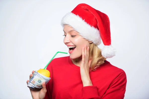 女圣诞老人帽子喝果汁柠檬包裹在钞票。完全天然柠檬汁。用吸管喝新鲜的柠檬水饮料。财富和丰富的象征。带着柠檬和钱的女孩柠檬钱的概念 — 图库照片