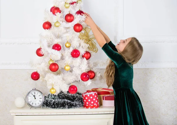 Ребенок вешает рождественский орнамент на искусственное дерево. Дети могут осветить елку, создавая свои собственные украшения. Девочка празднует Рождество. Главная рождественские украшения идеи для детской комнаты — стоковое фото