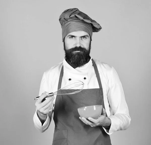 Chef avec assiette et ustensile à fouetter. Cuisiner avec un visage sérieux — Photo