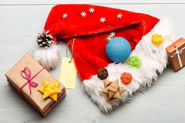 新年和圣诞装饰品。圣诞老人帽子和圣诞礼品盒。圣诞老人送的圣诞礼物圣诞老人帽子白色背景顶视图。气氛就是细节。寒假属性 — 图库照片