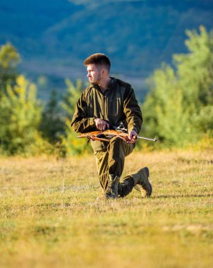 Avcılık atıcılık kupa. Avcı tüfeği hayvan için arıyorum. Adam şarj av tüfeği. Erkek hobi ve eğlence avcılık. Silah Dağları arka plan avcı haki elbise avlamak hazır tutun