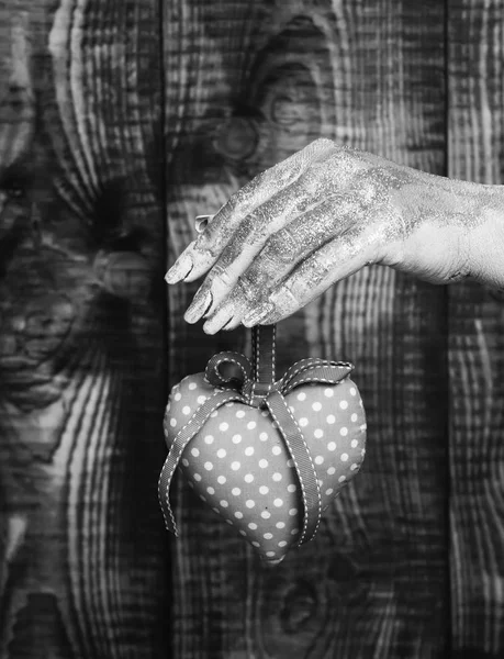 Ženská ruka namazané zlatou malbou nebo glister drží ručně růžové puntíky valentine srdce na hnědý vintage studio pozadí, selektivní focu — Stock fotografie