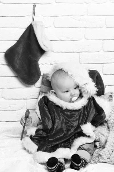 Mały chłopczyk z adorable curious oblicze w czerwonym swetrze z manekina w hodowli kapelusz i Boże Narodzenie lub Boże Narodzenie nowy rok lub rozruchu na tle ściany Cegła biała — Zdjęcie stockowe