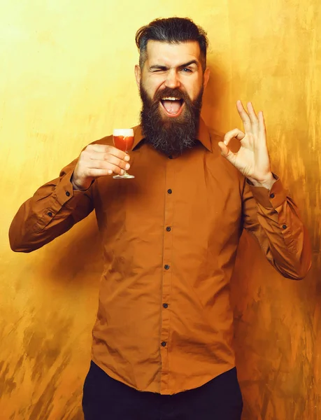 髭を生やした男長い髭。ブルータルcaucasian笑顔幸せなヒップスターとともに口ひげでブラウンシャツ保持アルコール赤ショットと上のokを示す黄金のテクスチャの背景 — ストック写真