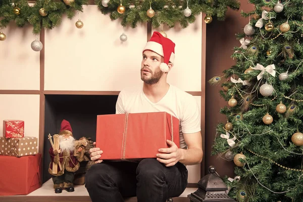 Chico con cara seria en santa hat hold present box — Foto de Stock