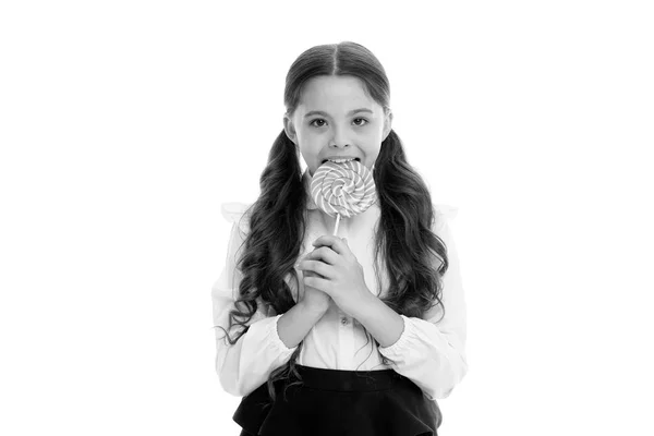 Genieten van heerlijk snoep. Meisje schattig kind paardenstaarten kapsel eet zoete lolly. Snoep in de juiste porties ok. Meisje leerling school uniform houdt van snoep lolly snoep geïsoleerde witte achtergrond — Stockfoto