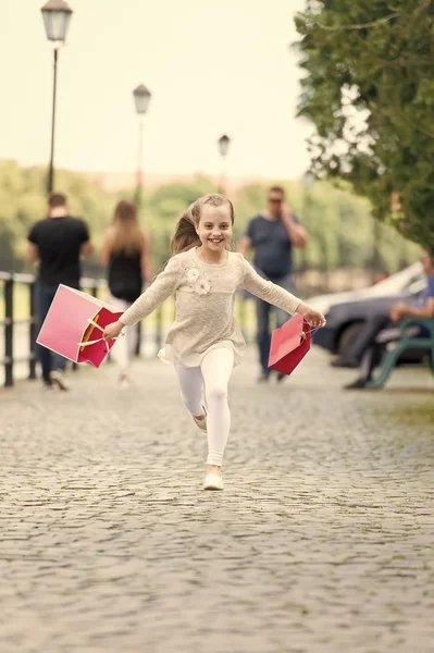 Досить маленька дівчинка працює на вулиці з рожевими сумками для покупок — стокове фото