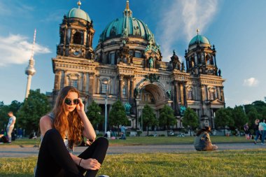 Berlin Katedrali 'nin önünde güneş kremi sürerek oturuyor.