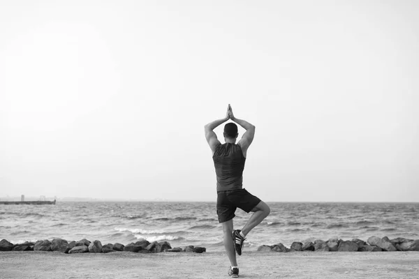 Trouvez l'équilibre et unissez-vous à la nature. La pratique du yoga aide à trouver l'harmonie et l'équilibre. Homme pratiquant yoga mer plage fond. Un endroit paisible. Atteint la tranquillité d'esprit. Concept de sérénité et harmonie — Photo