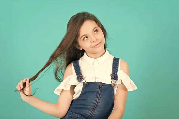Kid flicka med tänkande ansikte håller länge brunett hår — Stockfoto