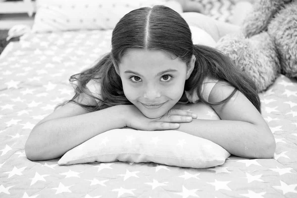 Travesseiro confortável. Menina sorrindo criança feliz deitada na cama com almofadas padrão estrela e xadrez bonito em seu quarto. Roupa de cama para crianças. Miúda a acordar de manhã. Roupa de cama moderna e elegante — Fotografia de Stock