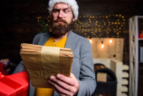 Post for santa claus. Man bearded hipster wear santa hat hold bunch of letters and gift box. Letter for santa claus. Man mature bearded with eyeglasses received post for santa. Gifts delivery service