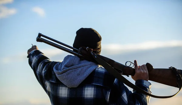 Guy Hunter pasa tiempo libre cazando. Hombre tipo brutal guardabosques en el fondo de la naturaleza sombrero. Caza masculina hobby concepto de ocio. Brutalidad y masculinidad. Hunter llevar pistola de rifle en el hombro vista trasera — Foto de Stock