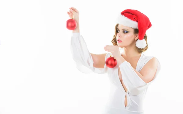 Προετοιμασία για τα Χριστούγεννα. Γυναίκα φορούν σέξι φόρεμα και santa καπέλο κρατήστε διακοσμητικές μπάλες σε άσπρο φόντο. Κορίτσι με μακιγιάζ και χτένισμα έτοιμοι για το Χριστουγεννιάτικο πάρτι. Μακιγιάζ και ντύσιμο για Χριστουγεννιάτικο πάρτι — Φωτογραφία Αρχείου