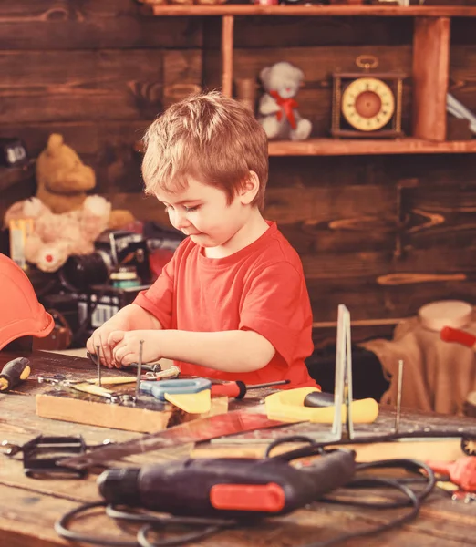 El niño juega como manitas. Niño lindo y adorable jugando con herramientas como constructor o reparador, reparación o artesanía. Niño en la cara ocupada juega con herramientas en casa en el taller. Concepto de infancia — Foto de Stock