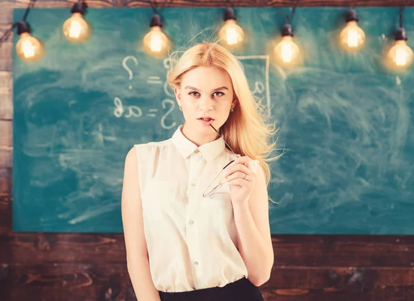 Sexy Lehrerkonzept. Frau mit langen Haaren in weißer Bluse steht im Klassenzimmer. Lehrerin mit Brille und wehendem Haar sieht sexy aus. Strenge Lehrerin mit verträumtem Gesicht steht vor Tafel — Stockfoto