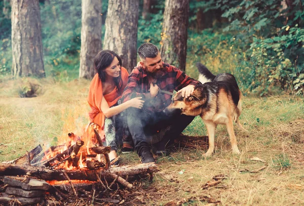 Couple play with german shepherd dog near bonfire,